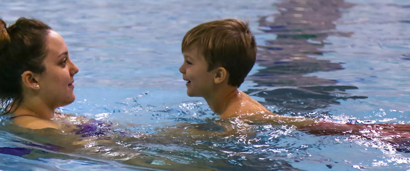 instructor in water with young child