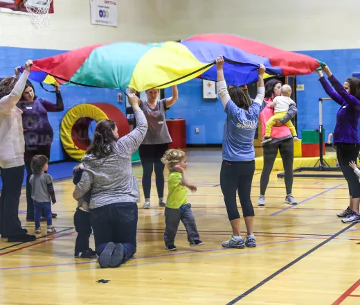 parents holding parachute with kids underneath