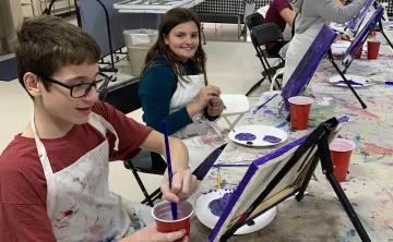 boy painting at table easle